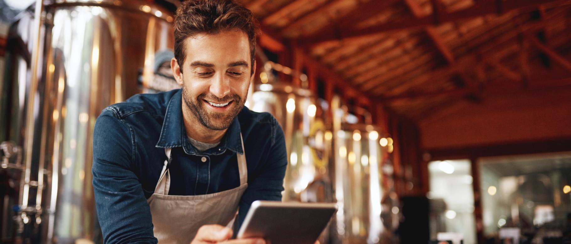 A mean uses a tablet inside a brewery