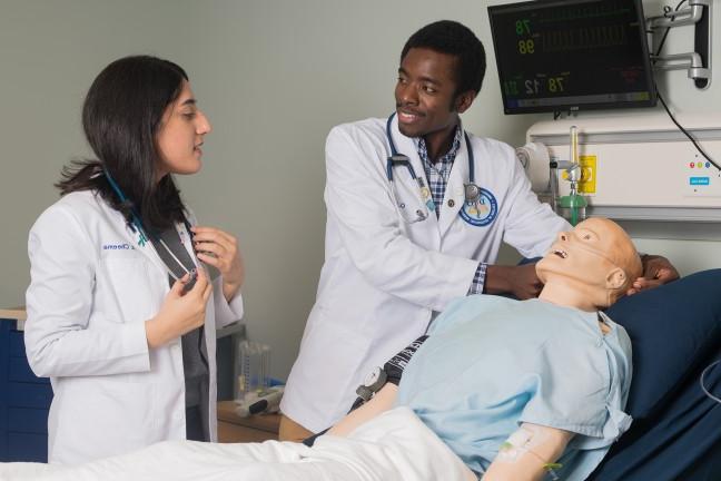 two students work on a patient simulator